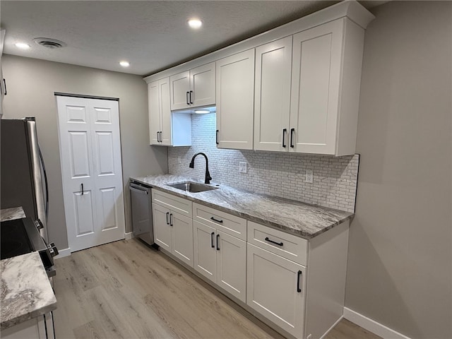 kitchen with appliances with stainless steel finishes, light stone countertops, sink, and white cabinets