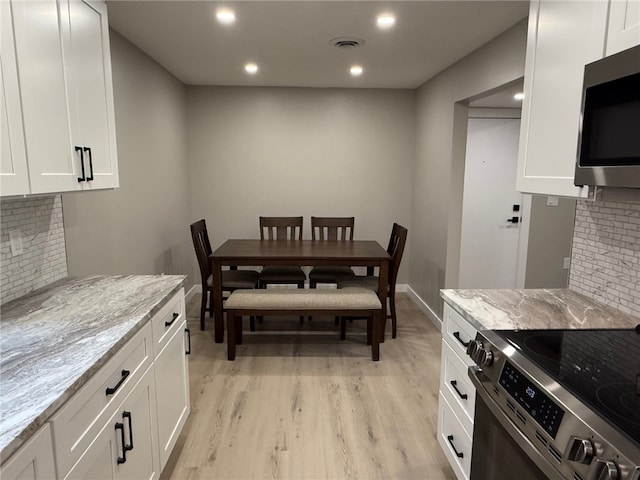 kitchen featuring appliances with stainless steel finishes, light stone countertops, and white cabinets