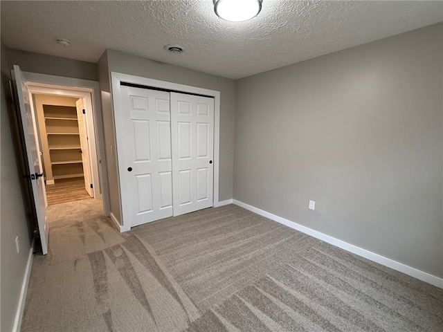 unfurnished bedroom featuring light colored carpet, a closet, and a textured ceiling