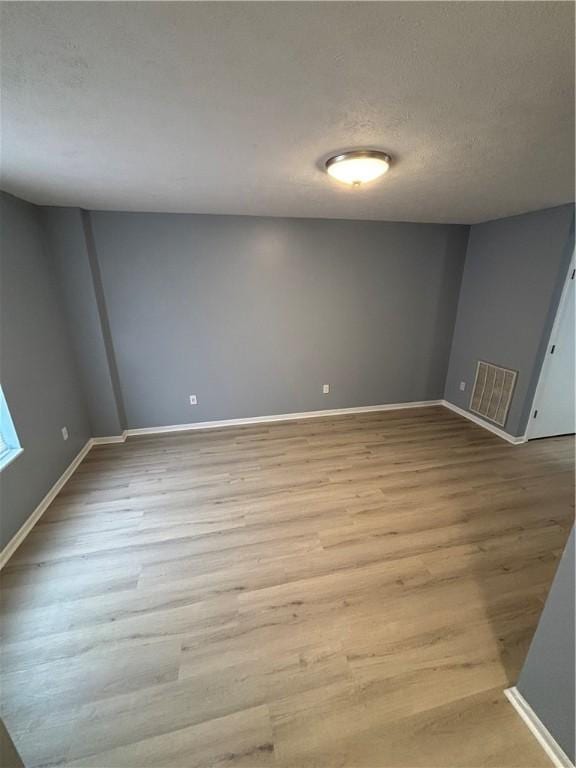 spare room with a textured ceiling and light hardwood / wood-style flooring