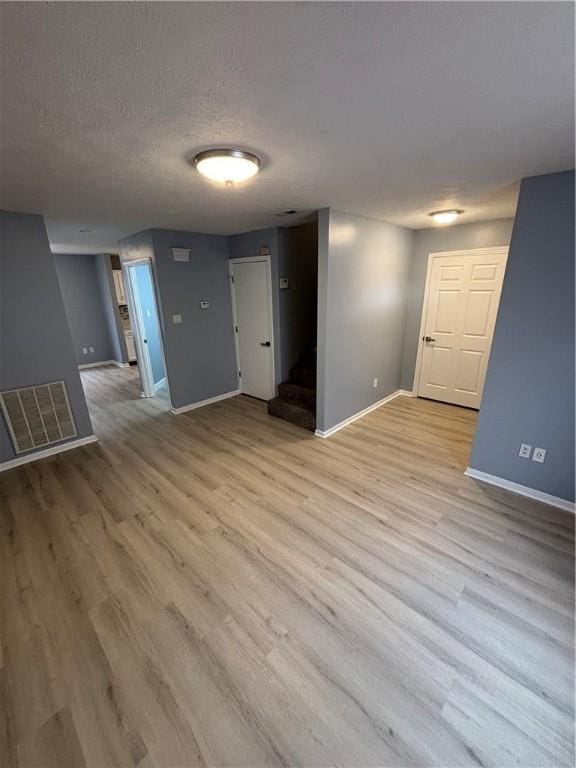 unfurnished room with a textured ceiling and light wood-type flooring