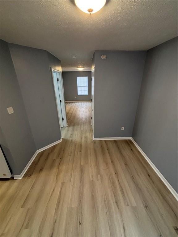 unfurnished room featuring a textured ceiling and light wood-type flooring