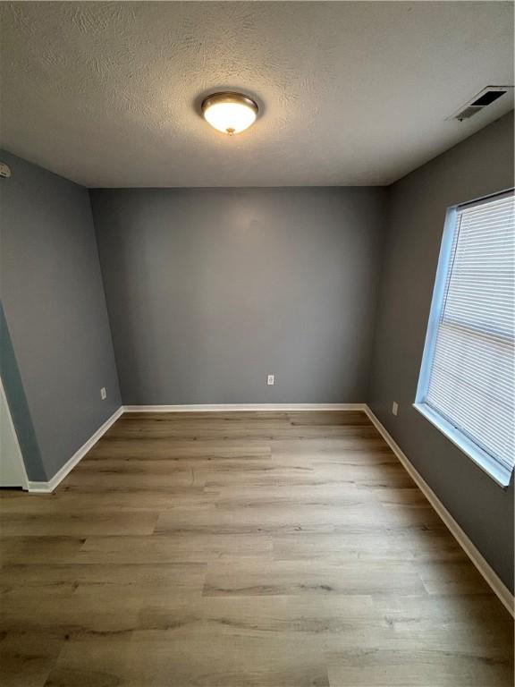 unfurnished room featuring light hardwood / wood-style flooring and a textured ceiling