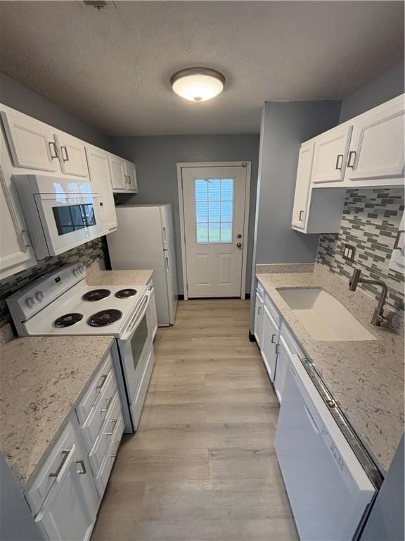 kitchen with sink, white cabinetry, light hardwood / wood-style flooring, white appliances, and backsplash