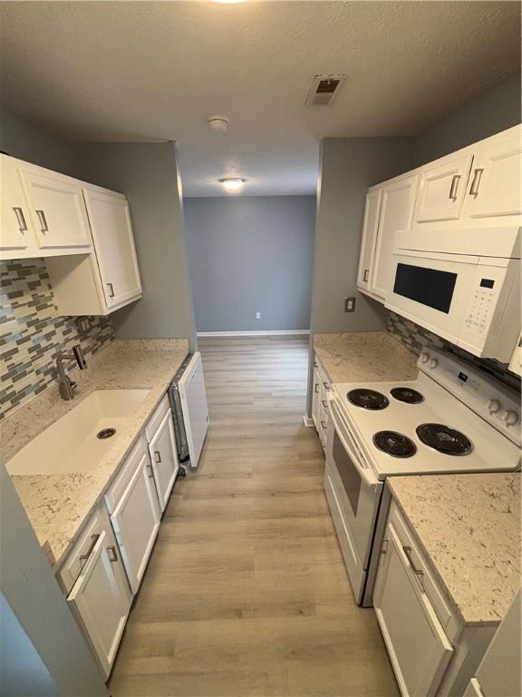 kitchen featuring sink, white appliances, tasteful backsplash, white cabinets, and light wood-type flooring