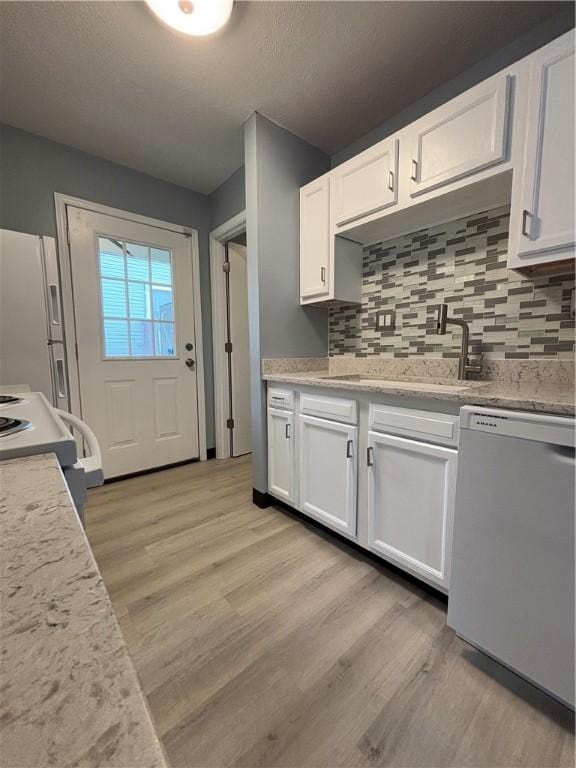 kitchen featuring sink, white appliances, tasteful backsplash, white cabinets, and light wood-type flooring