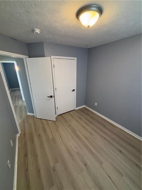 unfurnished bedroom with light hardwood / wood-style floors and a textured ceiling