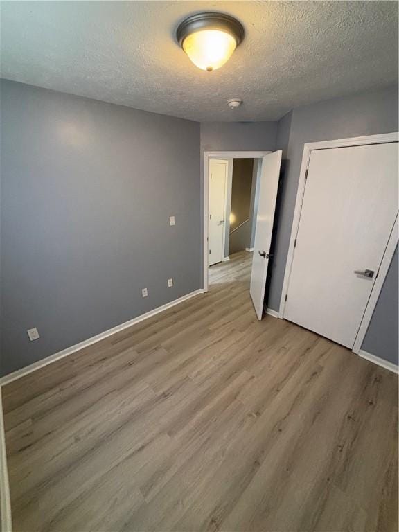 spare room with a textured ceiling and light hardwood / wood-style flooring