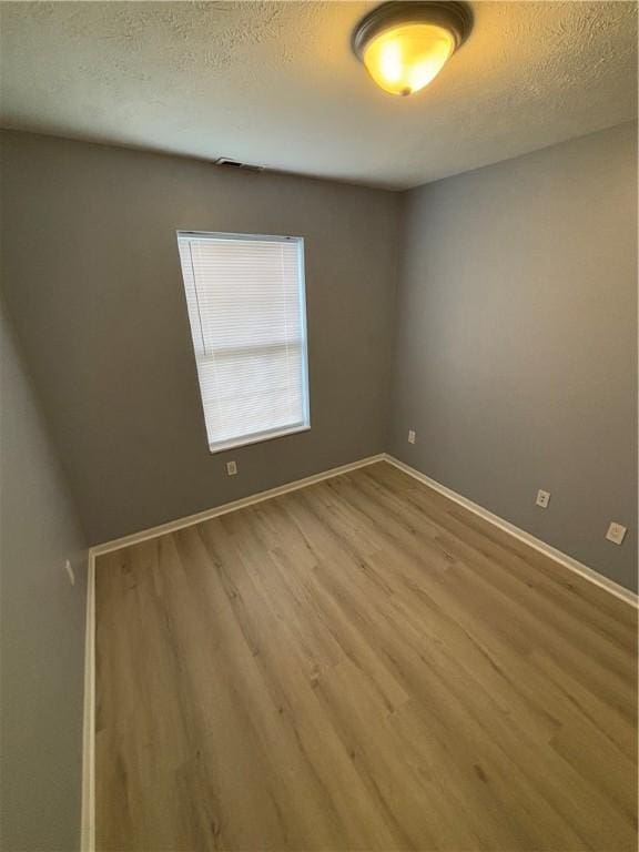 empty room with hardwood / wood-style flooring and a textured ceiling