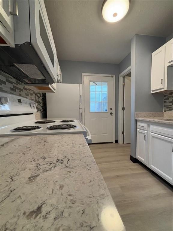 kitchen with white electric range, range hood, white cabinetry, decorative backsplash, and light hardwood / wood-style flooring