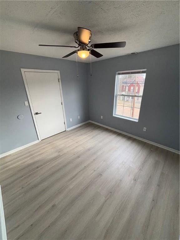 empty room with a textured ceiling and light wood-type flooring