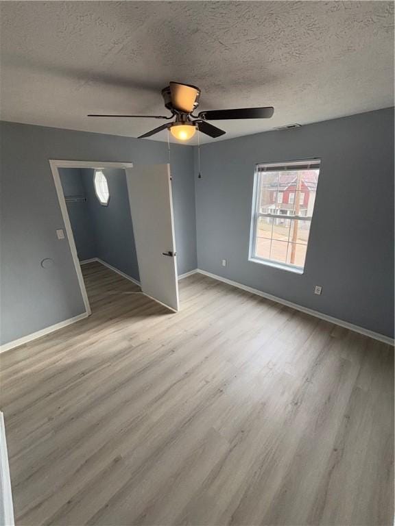 empty room featuring a textured ceiling and light hardwood / wood-style flooring