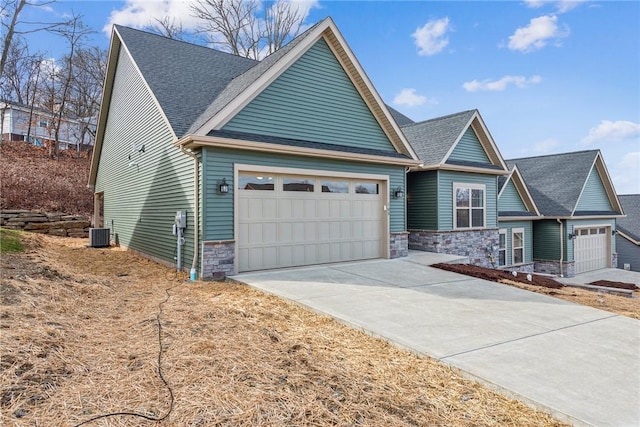 craftsman-style house featuring a shingled roof, stone siding, driveway, and an attached garage