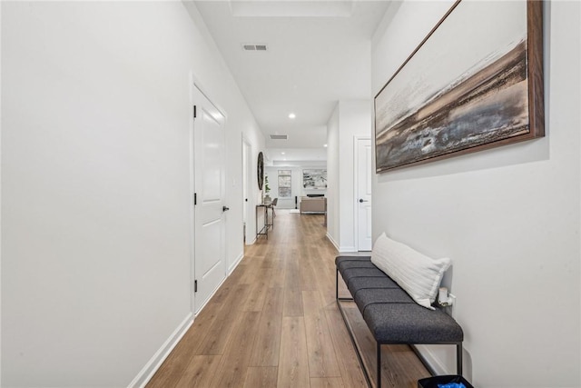 hall featuring light wood-type flooring, baseboards, visible vents, and recessed lighting