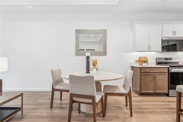 dining space featuring light wood-style flooring and baseboards