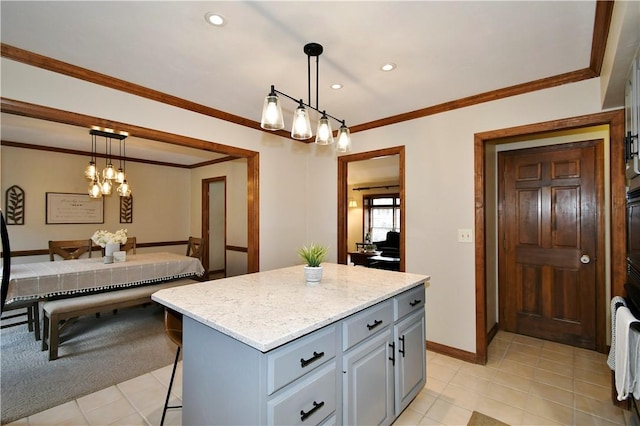 kitchen with pendant lighting, crown molding, gray cabinetry, a kitchen island, and a kitchen bar