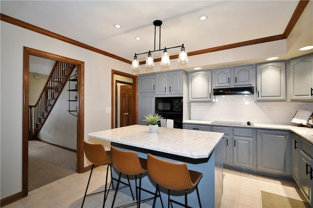 kitchen with crown molding, a kitchen island, backsplash, and black appliances