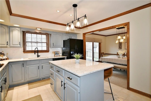 kitchen featuring black fridge with ice dispenser, sink, hanging light fixtures, ornamental molding, and a kitchen island