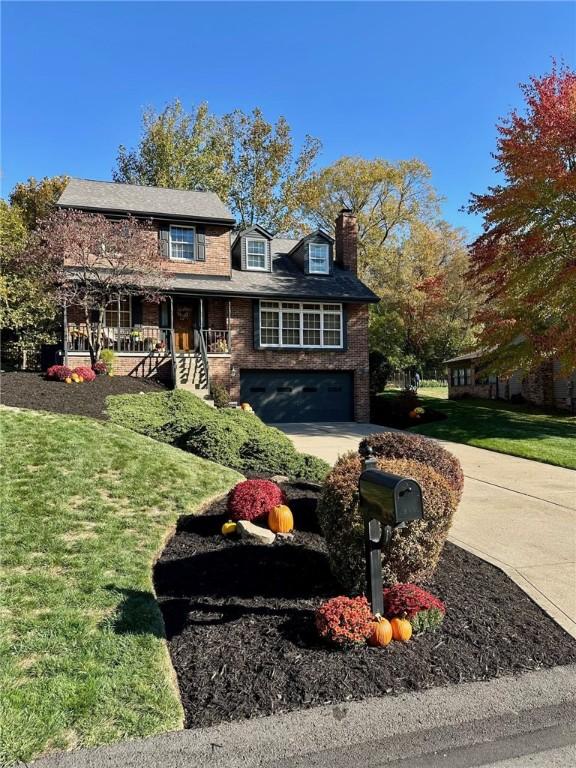 view of front of home with a garage, a front yard, and covered porch