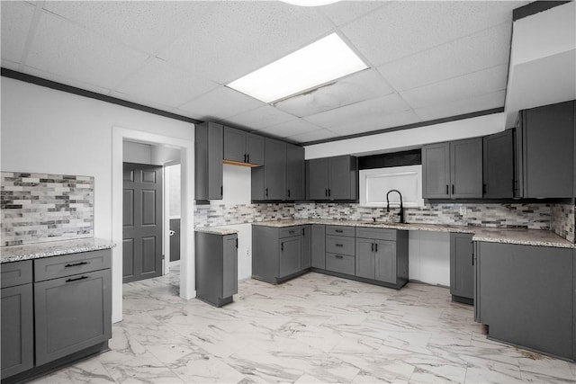 kitchen featuring gray cabinetry, sink, and tasteful backsplash