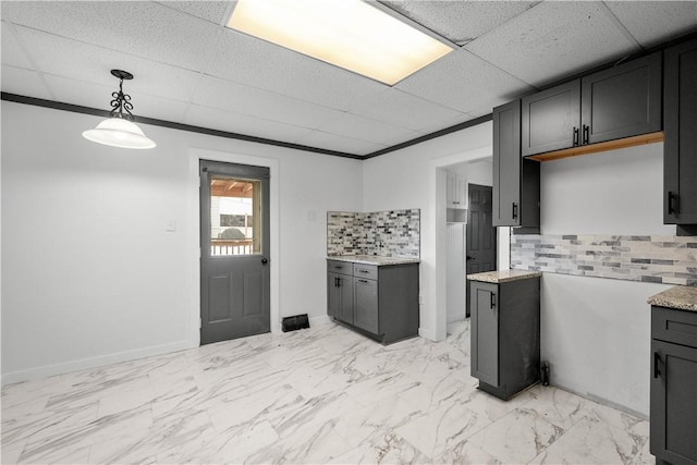 kitchen featuring tasteful backsplash, a paneled ceiling, and pendant lighting