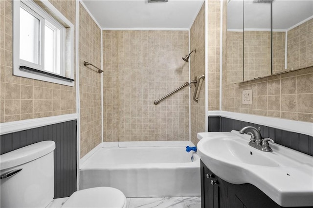 full bathroom featuring tile walls, tiled shower / bath combo, vanity, ornamental molding, and toilet