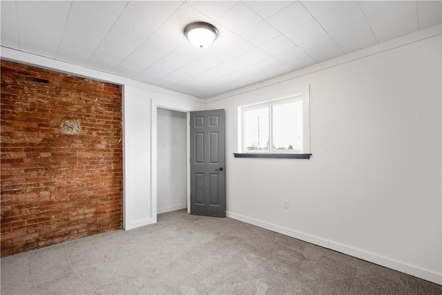 unfurnished bedroom featuring brick wall and carpet flooring