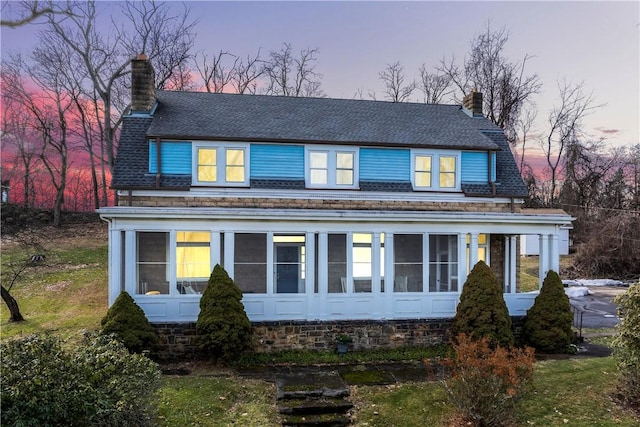 back house at dusk featuring a sunroom