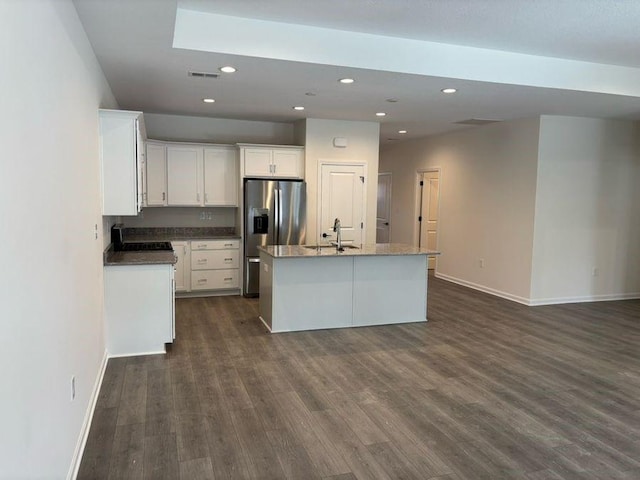 kitchen with sink, white cabinetry, an island with sink, dark hardwood / wood-style flooring, and stainless steel fridge with ice dispenser