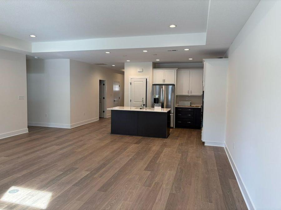 kitchen featuring sink, white cabinets, dark hardwood / wood-style flooring, a kitchen island with sink, and stainless steel refrigerator with ice dispenser