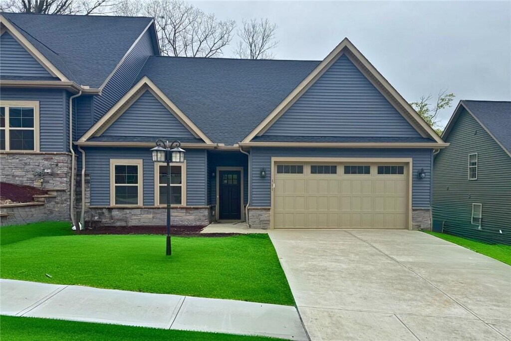 111 Hemingway Ln, Kennedy Twp, PA 15108 - craftsman-style home with stone siding, a front yard, concrete driveway, and an attached garage