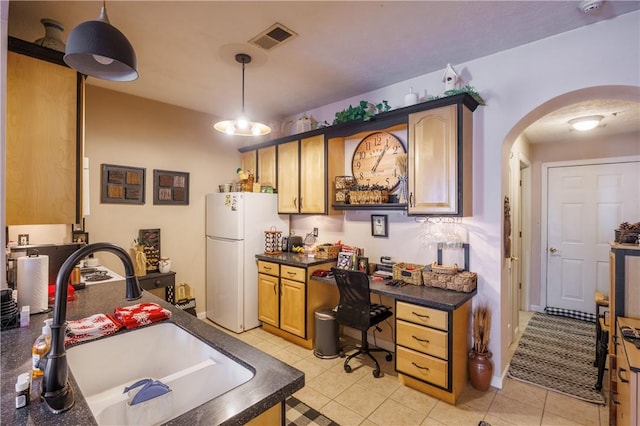 kitchen with pendant lighting, light tile patterned flooring, sink, and white fridge