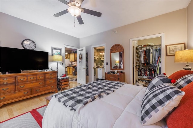 bedroom featuring ceiling fan, ensuite bathroom, a spacious closet, a closet, and light wood-type flooring