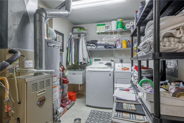 washroom featuring water heater, sink, washer and clothes dryer, light tile patterned floors, and a textured ceiling