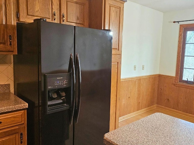 kitchen with black fridge and wood walls