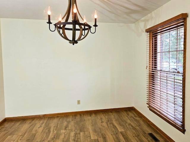 unfurnished dining area featuring a notable chandelier and wood-type flooring