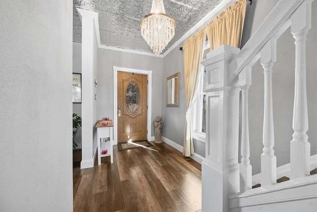 foyer entrance with a notable chandelier, dark wood-type flooring, and ornamental molding