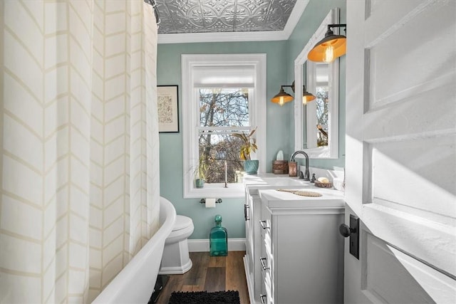 full bathroom featuring hardwood / wood-style flooring, crown molding, shower / tub combo, vanity, and toilet