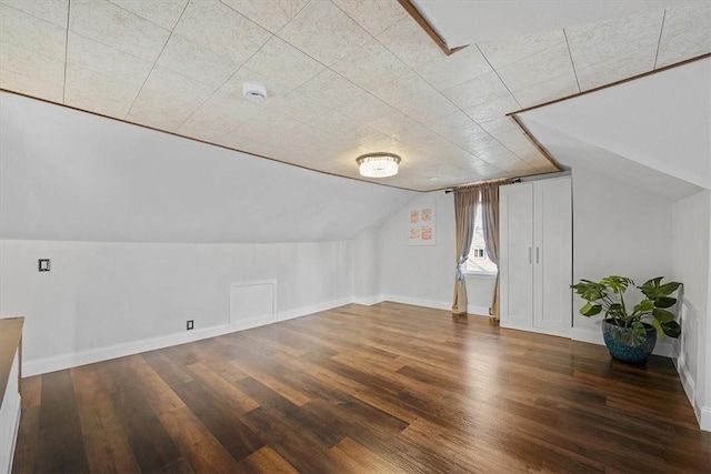 additional living space featuring dark wood-type flooring and vaulted ceiling