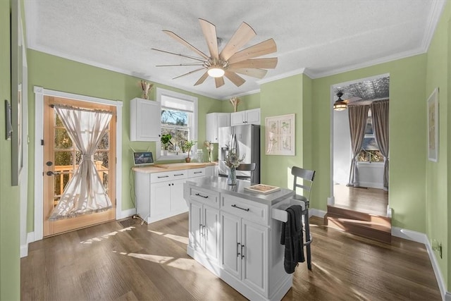 kitchen featuring white cabinetry, dark wood-type flooring, stainless steel fridge, and ornamental molding