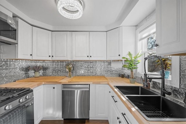 kitchen with butcher block counters, decorative backsplash, stainless steel appliances, and white cabinets