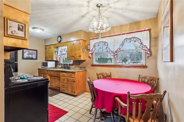 kitchen with hanging light fixtures, stove, light tile patterned floors, and a textured ceiling