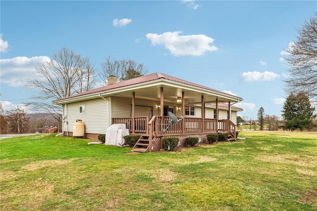 back of property with a wooden deck, a lawn, and ceiling fan