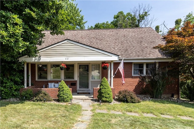 bungalow-style home with a front yard and covered porch