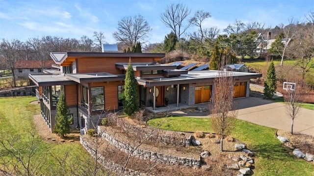 view of front of home with a garage, solar panels, and a front yard