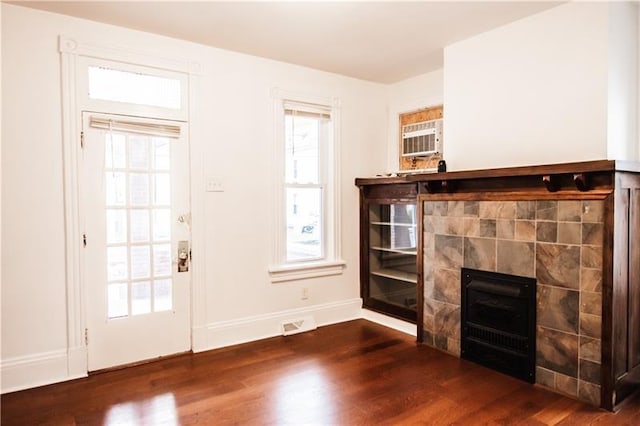 doorway featuring dark wood-type flooring, a healthy amount of sunlight, a fireplace, and an AC wall unit