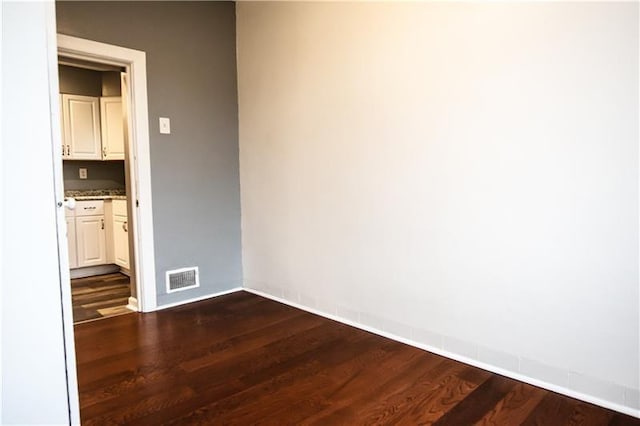 unfurnished room with dark wood-type flooring