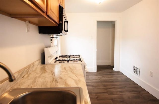 kitchen featuring sink, white range with gas cooktop, and dark wood-type flooring