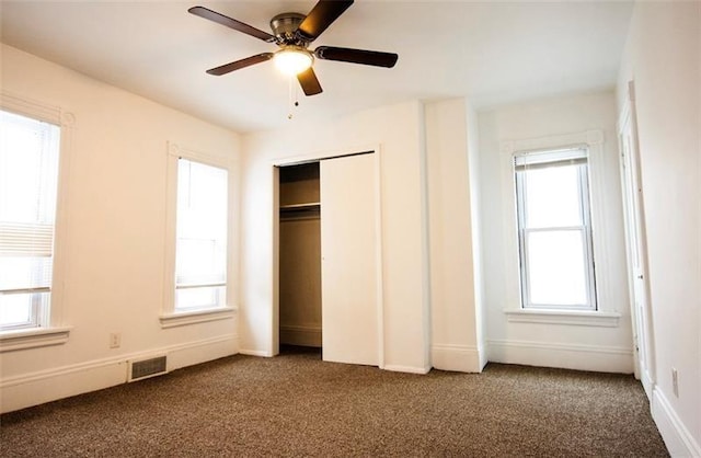 unfurnished bedroom with dark carpet, a closet, and ceiling fan