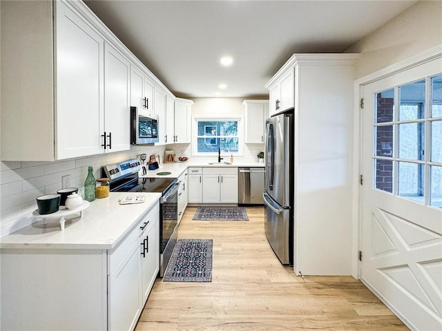 kitchen featuring white cabinetry, stainless steel appliances, light hardwood / wood-style floors, and tasteful backsplash